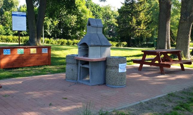 dwa grille oraz stoły z ławkami na terenach zielonych w okolicach mostu na wyspę